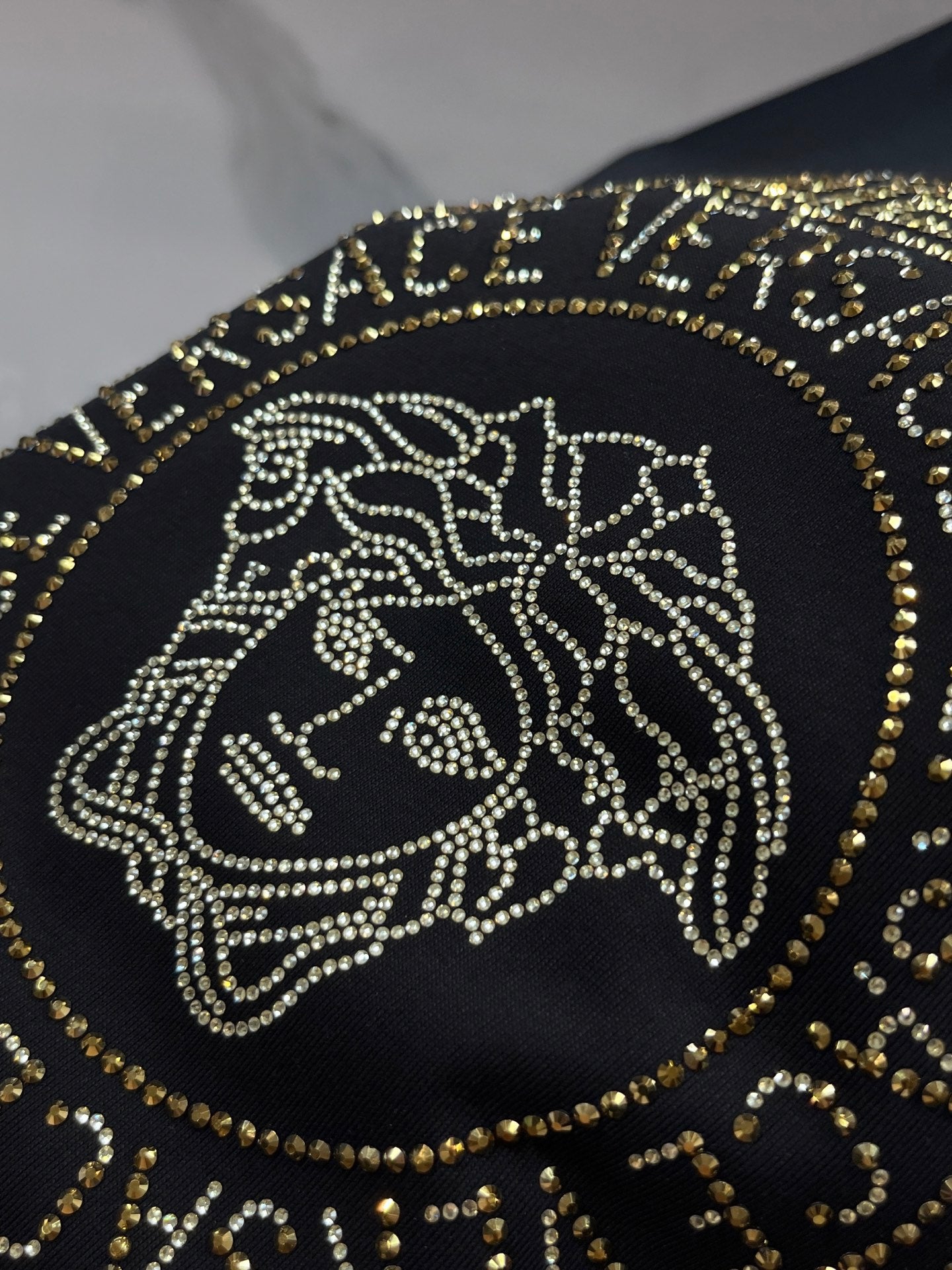 Versace black T-shirt close-up of gold Medusa head emblem