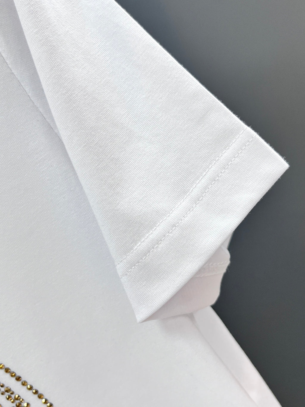 White T-shirt sleeve and hem detail, folded on a hanger