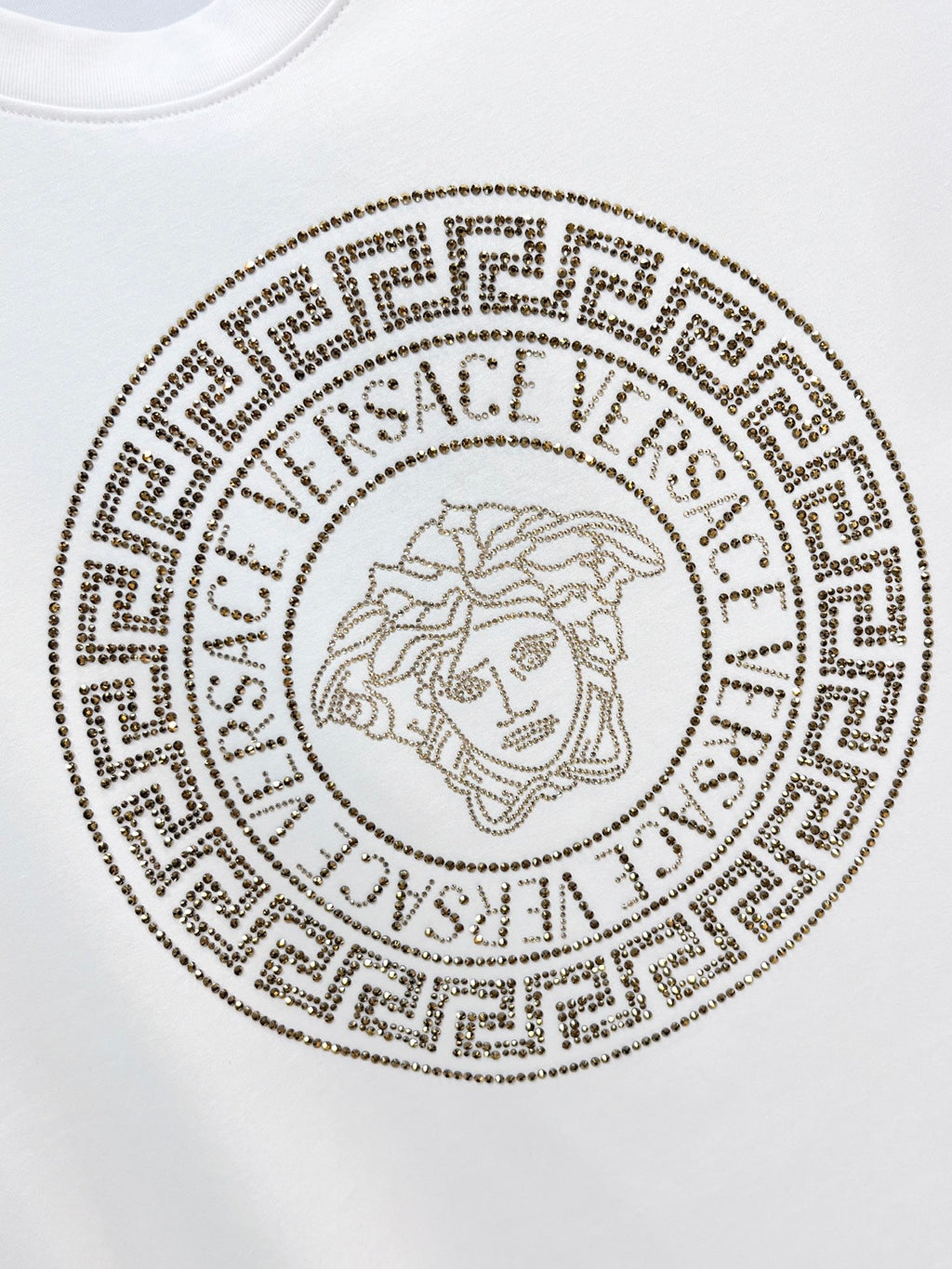 White T-shirt with circular gold Medusa-style logo emblem on the chest