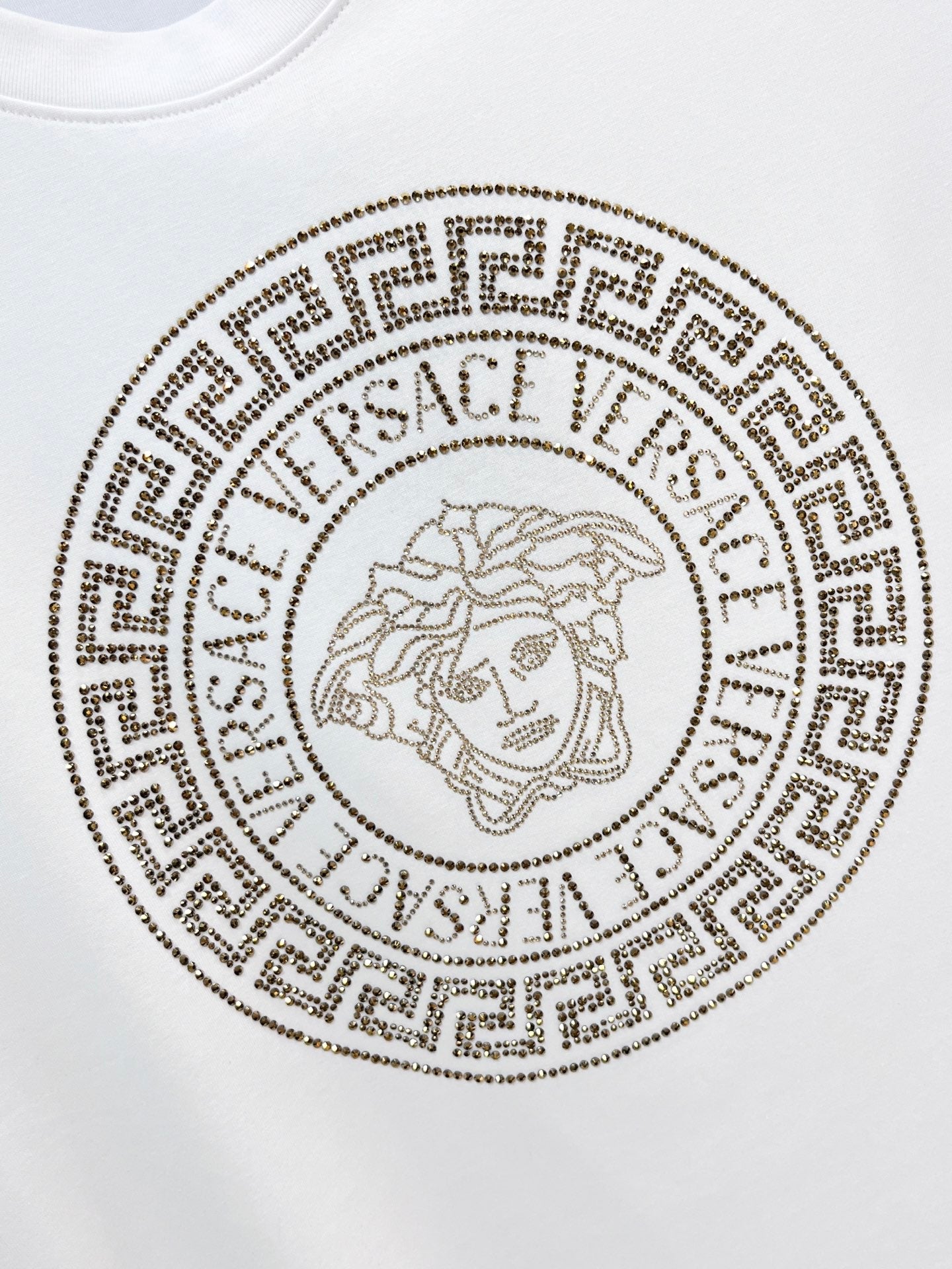White T-shirt with circular gold Medusa-style logo emblem on the chest