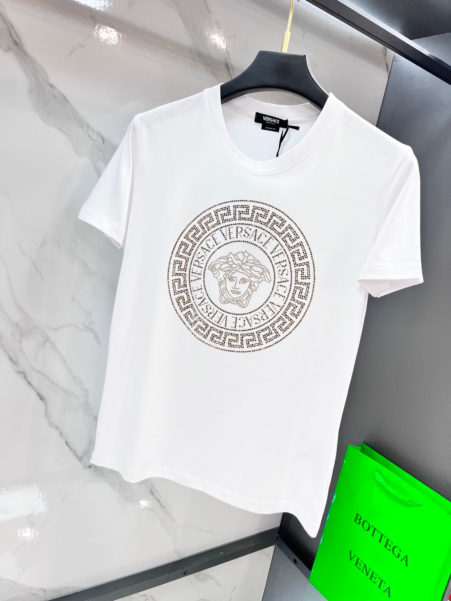 White T-shirt with gold Medusa-style emblem logo on front