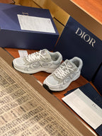 Light gray sneakers shown at an angle with lace-up closure and logo detailing