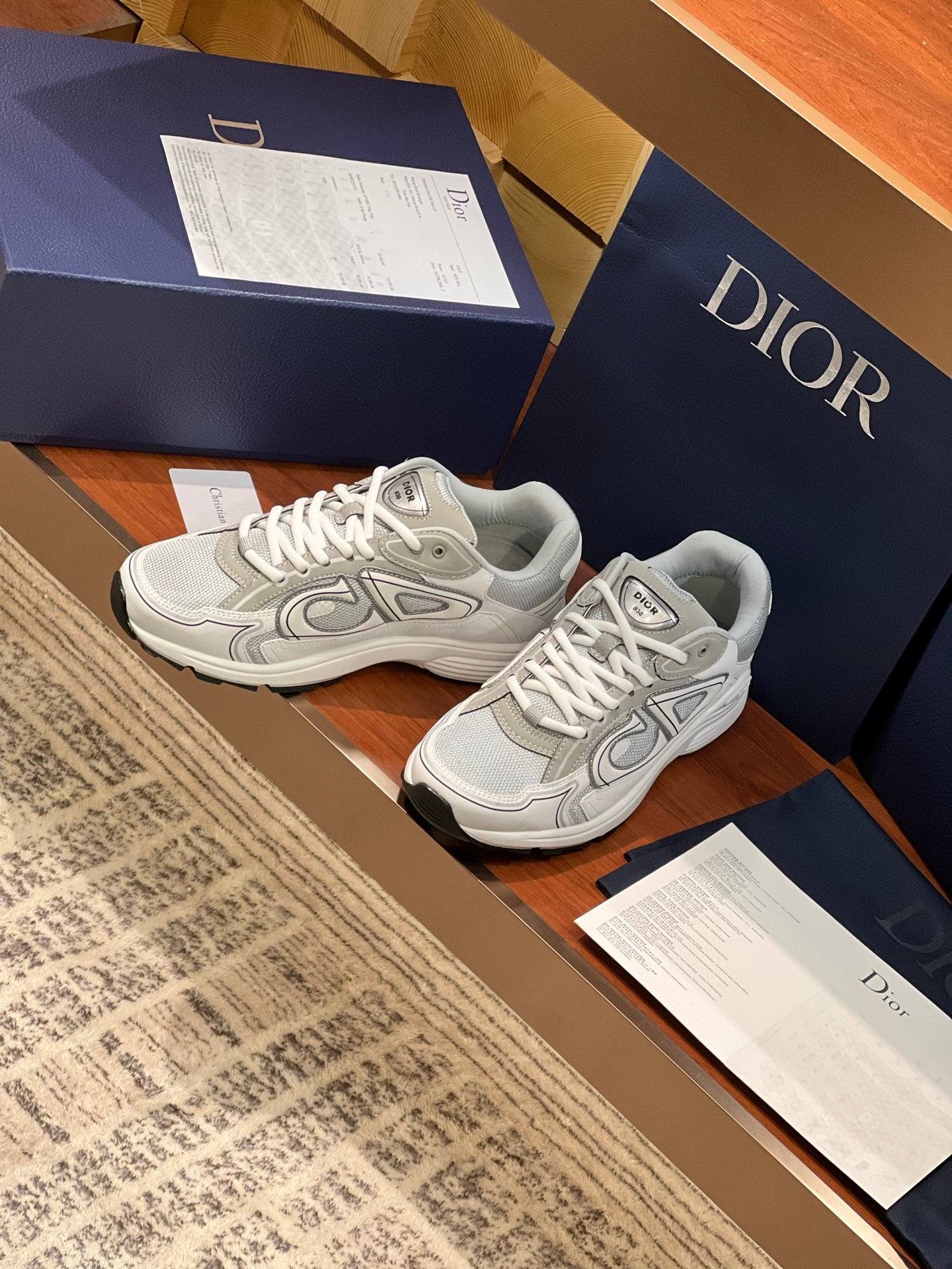 Light gray sneakers shown at an angle with lace-up closure and logo detailing