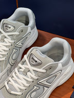 Close-up of light gray lace-up sneakers with logo patch on the tongue