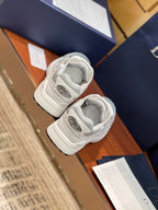 Two light gray sneakers resting with lace-up fronts and ribbed sole edges