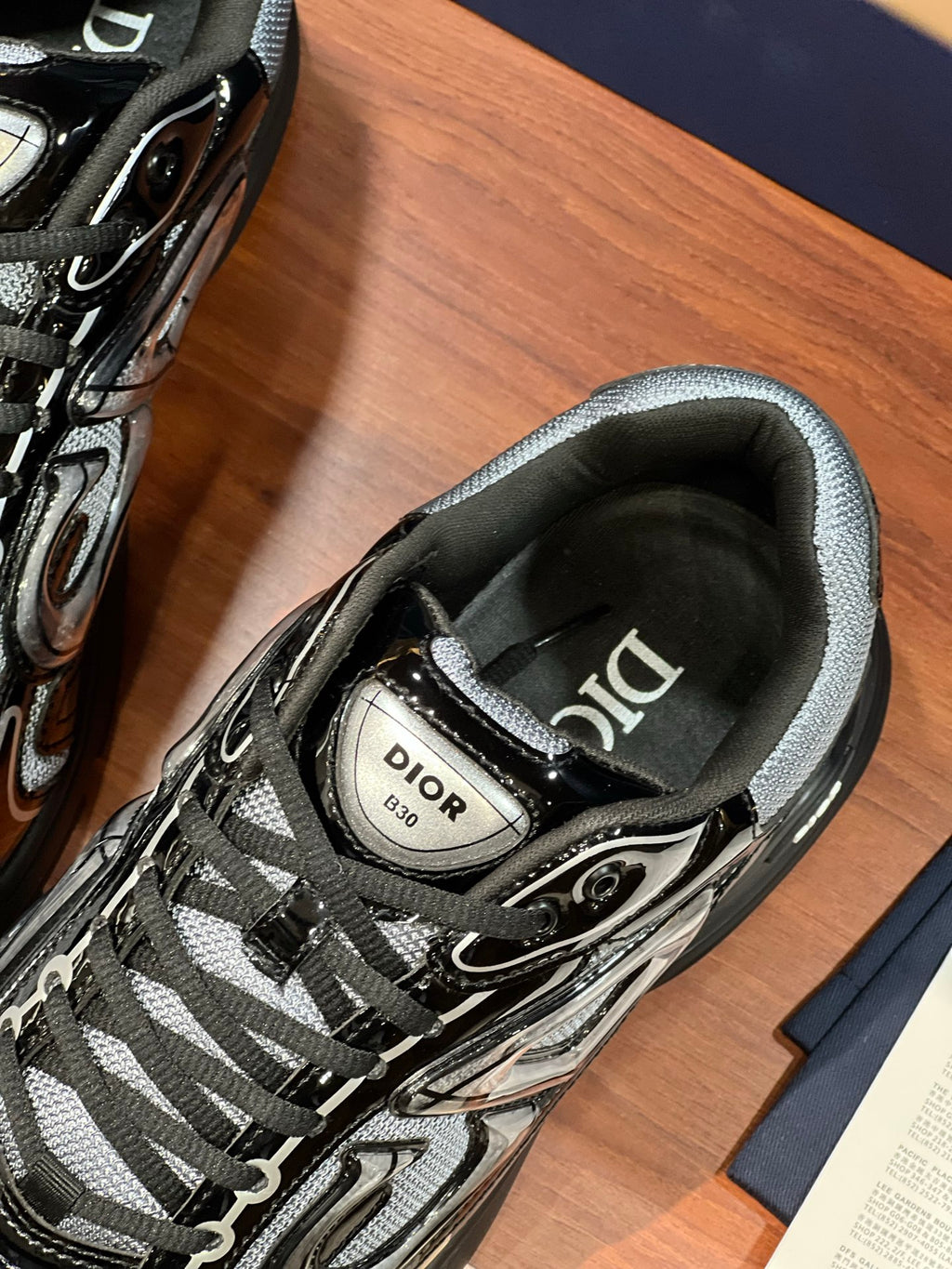 Close-up of black-and-gray lace-up sneaker tongue with Dior logo label