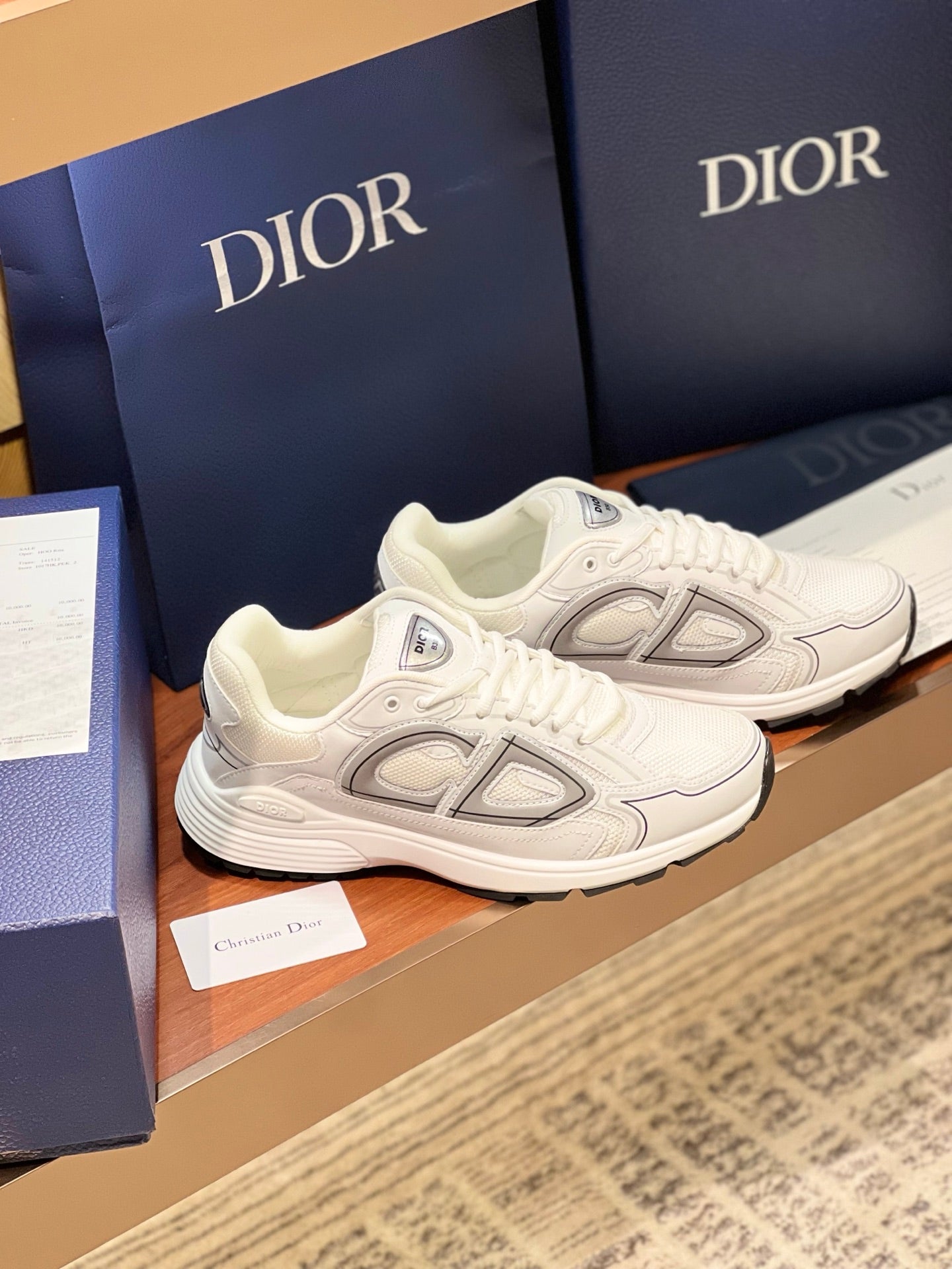 White Dior lace-up sneakers with gray side emblems and chunky sole, two-shoe angle