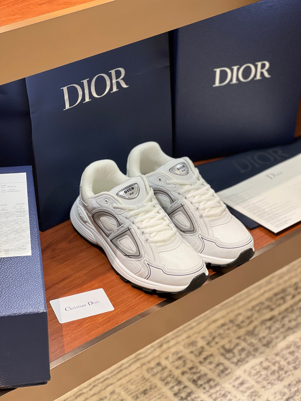 White Dior sneakers with gray side panels and lace-up design, thick rubber sole