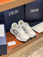 White Dior sneakers with gray side panels and lace-up design, thick rubber sole