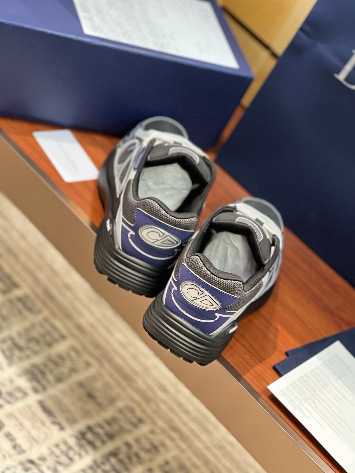 Lace-up sneakers rear view in gray and navy with black heel and ridged sole.