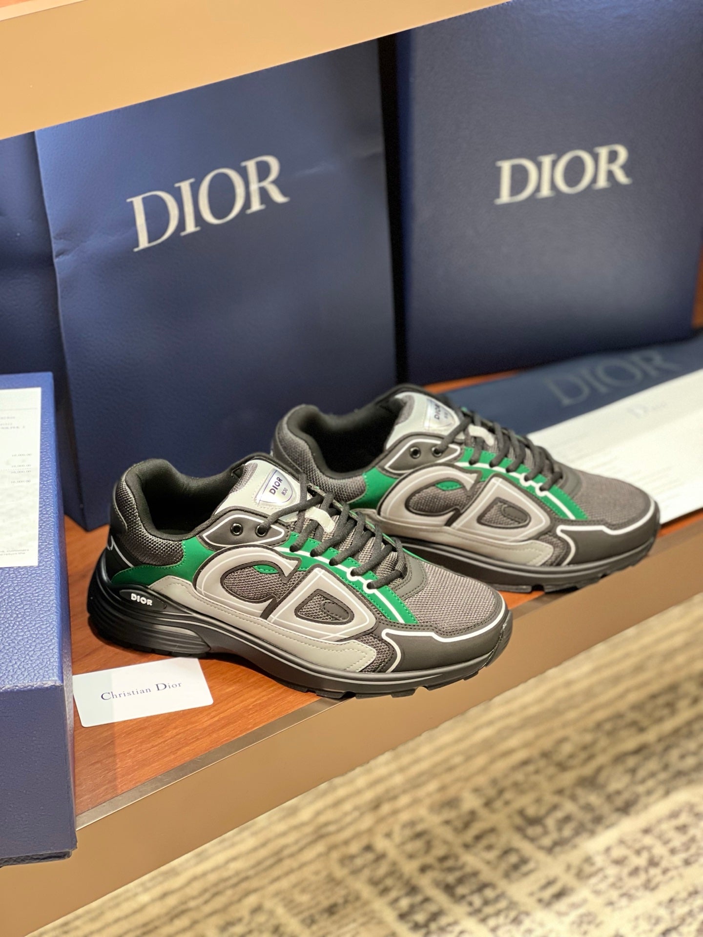 Dior ladies sneakers pair on shelf, grey uppers with green laces and white panels