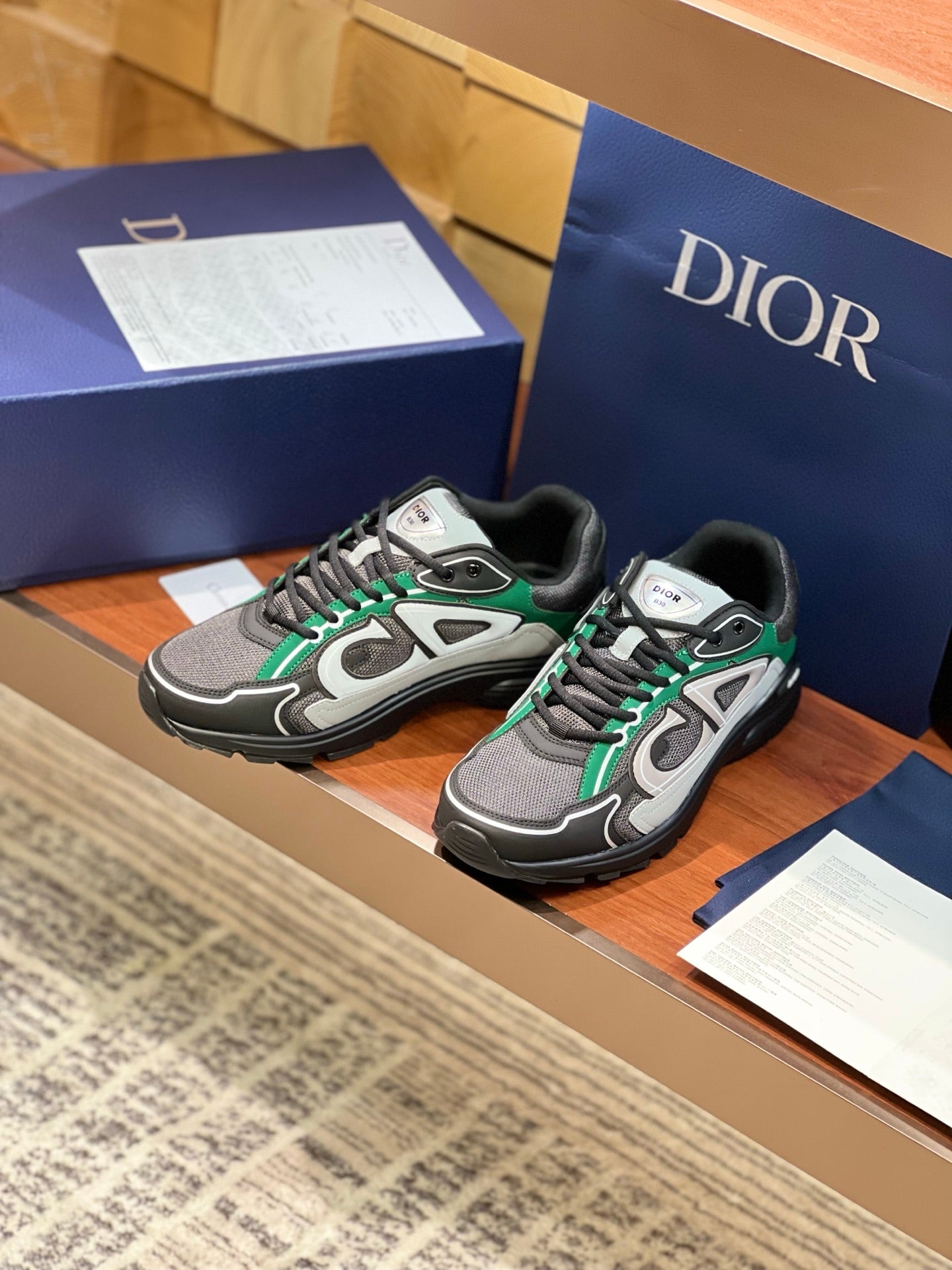 Dior ladies sneakers angled view, grey with green laces and white logo overlays