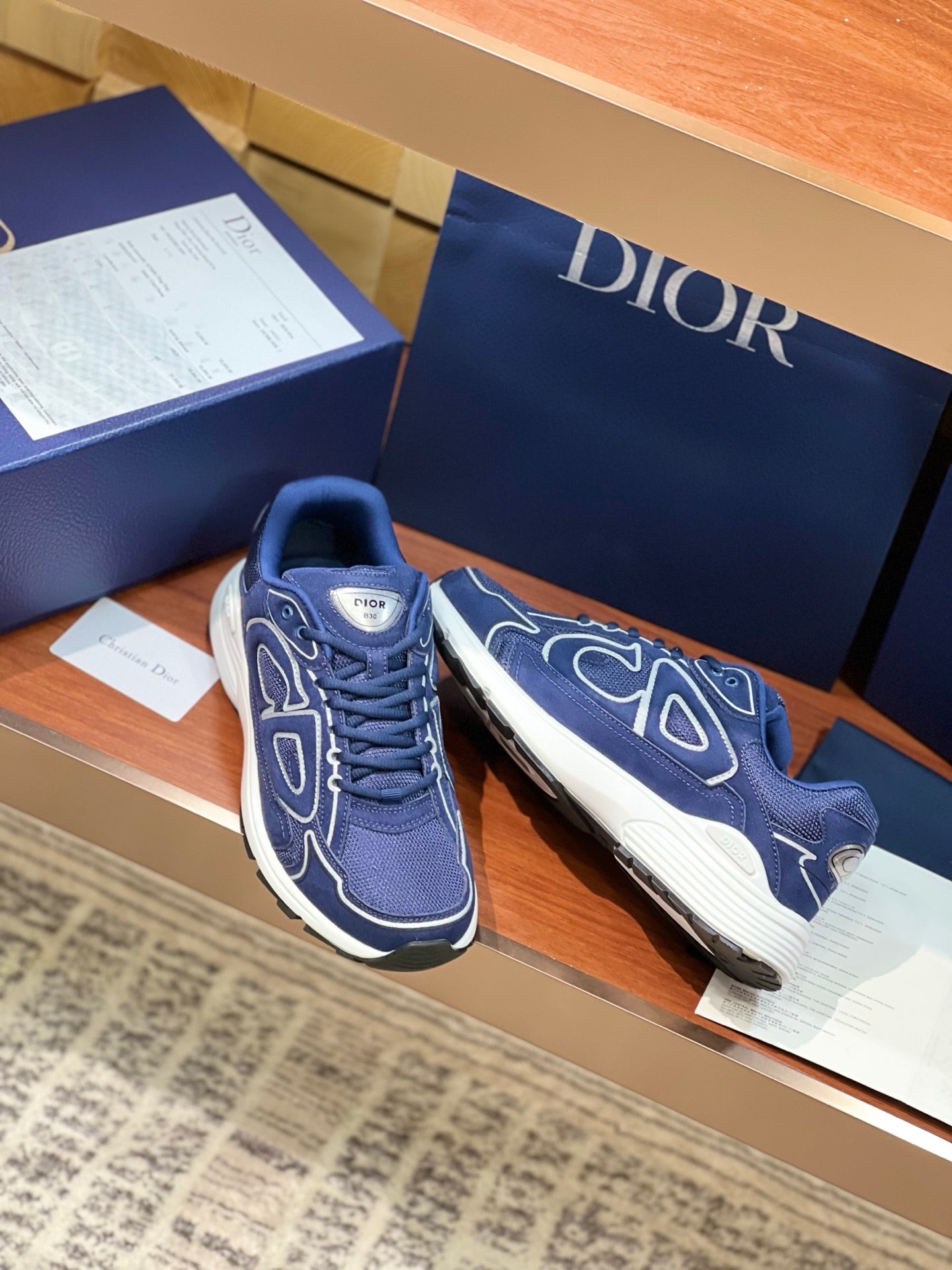 Navy Dior lace-up sneakers with white soles and logo pattern on uppers, close front