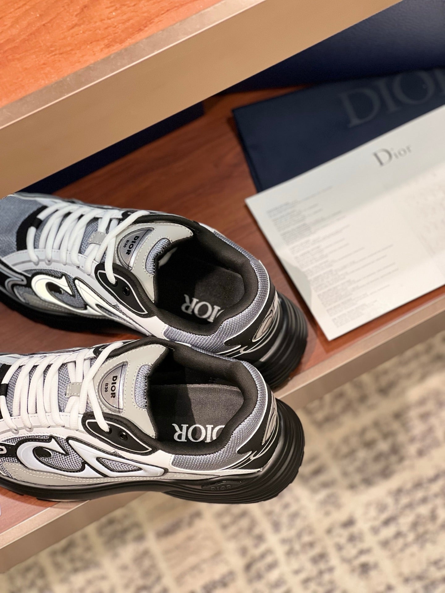 Dior low-top lace-up sneakers close-up, gray and black uppers with logo strap detail