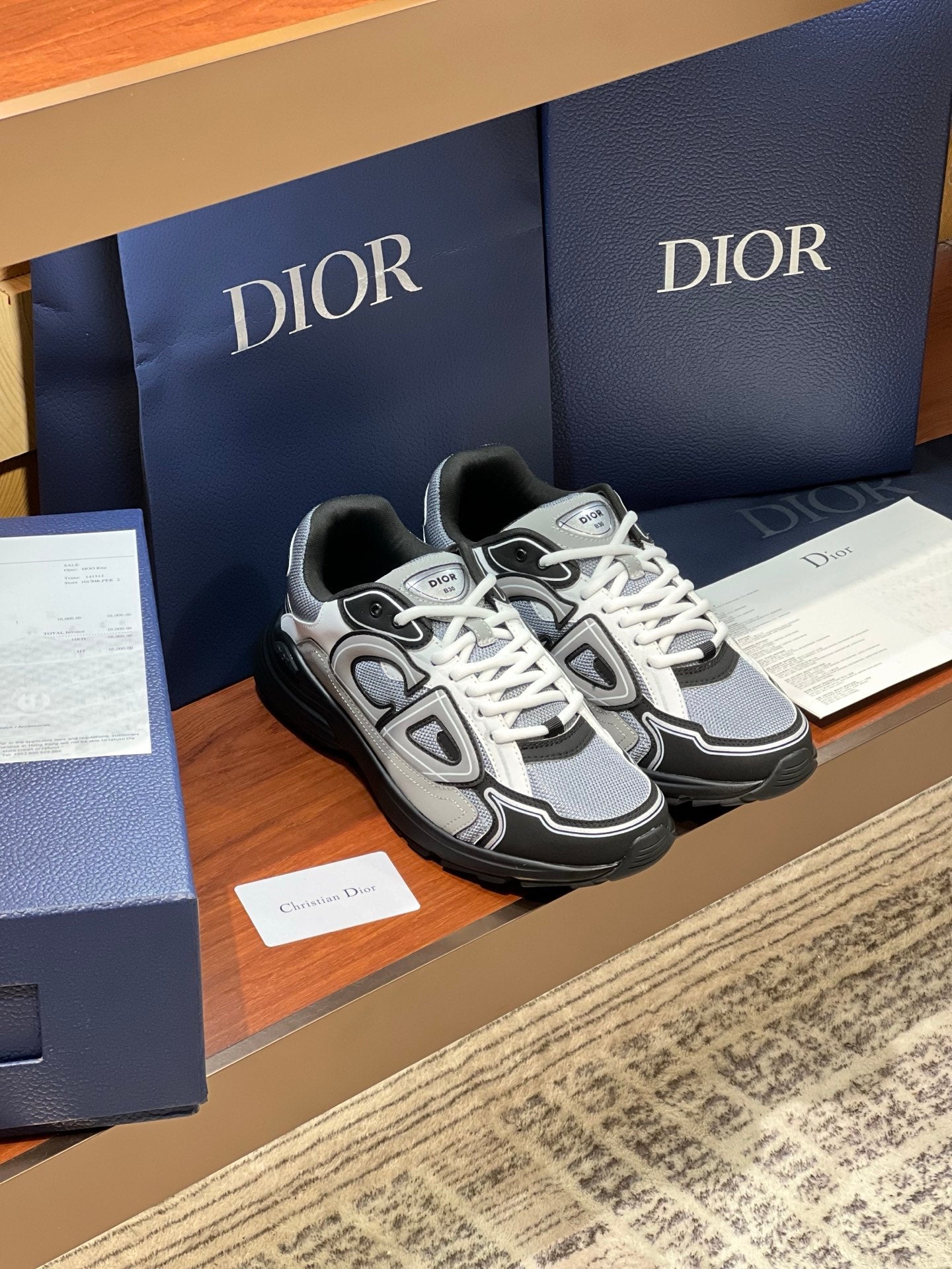Dior low-top lace-up sneakers with white laces, gray upper and black trim, logo detail