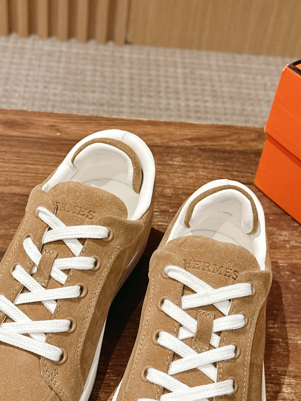 Pair of tan suede low-top sneakers with white laces, front view