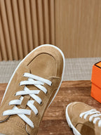 Tan suede low-top sneaker close-up with white laces and white sole trim
