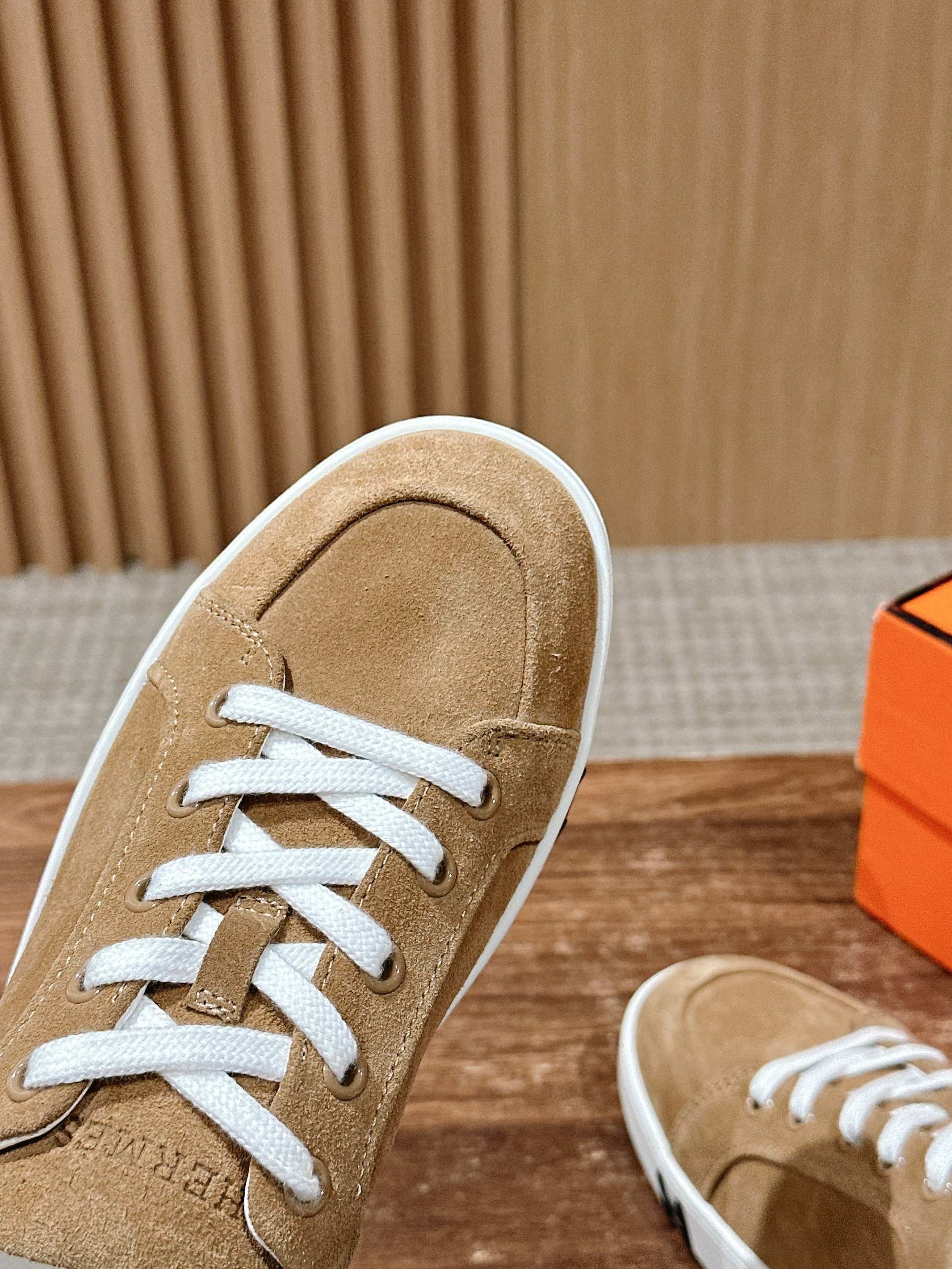 Tan suede low-top sneaker close-up with white laces and white sole trim