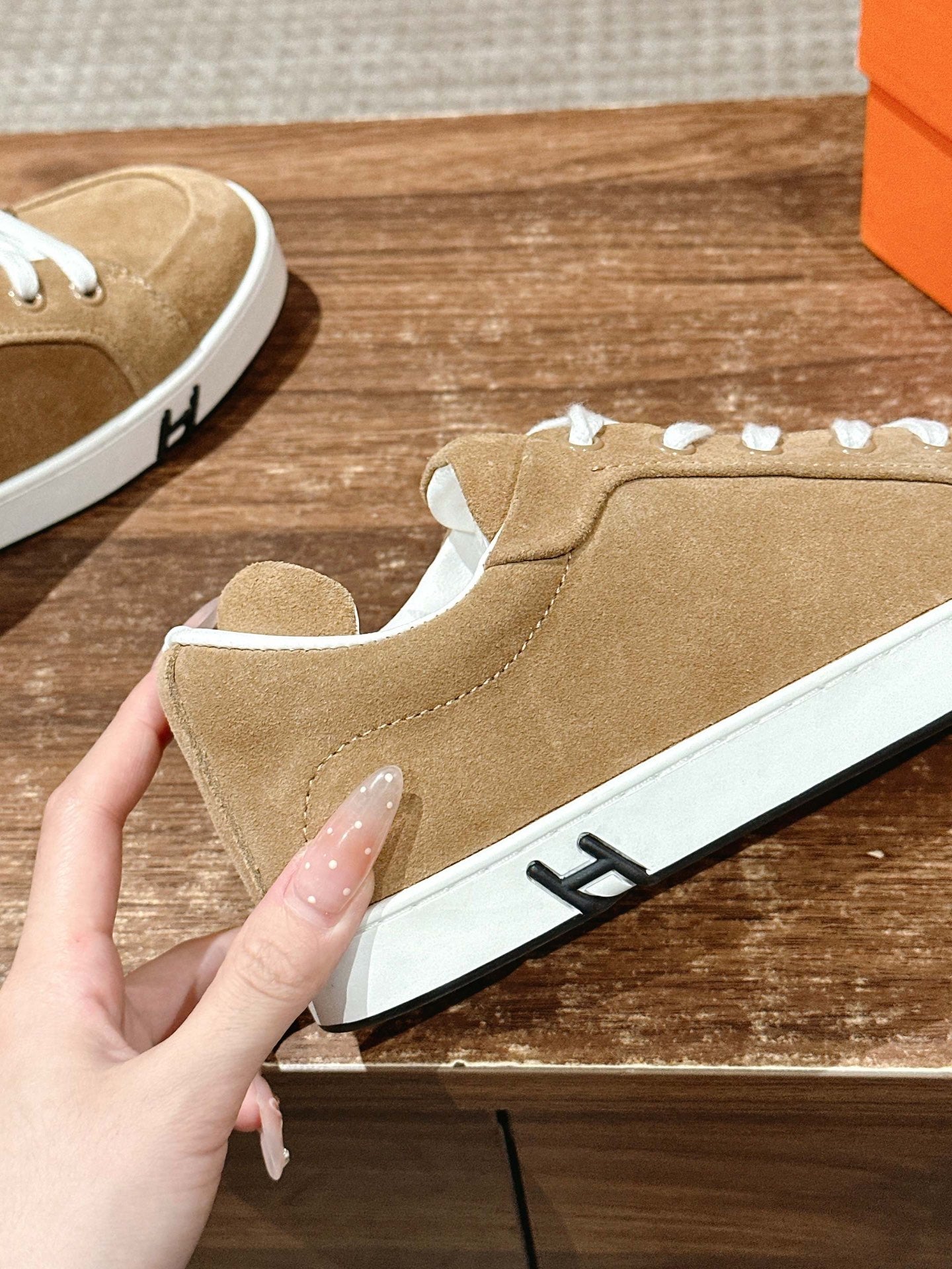 Tan suede low-top sneaker with white laces and black logo on side