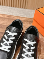 Hermes unisex black leather sneakers, front-and-side close-up with white laces