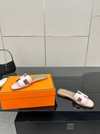 Ladies light pink leather slide sandals on orange box; open-toe with two strap closures