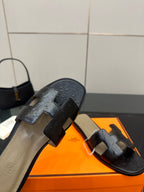 Black leather sandal slides showing heel side view and wide strap detail