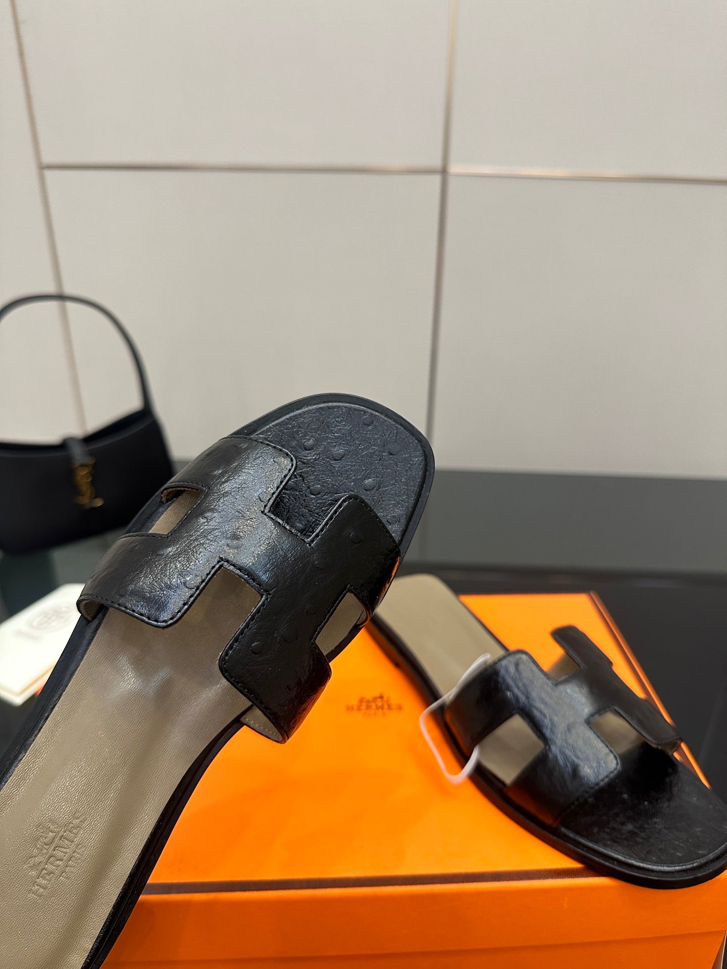 Black leather sandal slides showing heel side view and wide strap detail