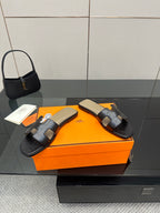 Black leather slide sandals with buckled straps and cream lining