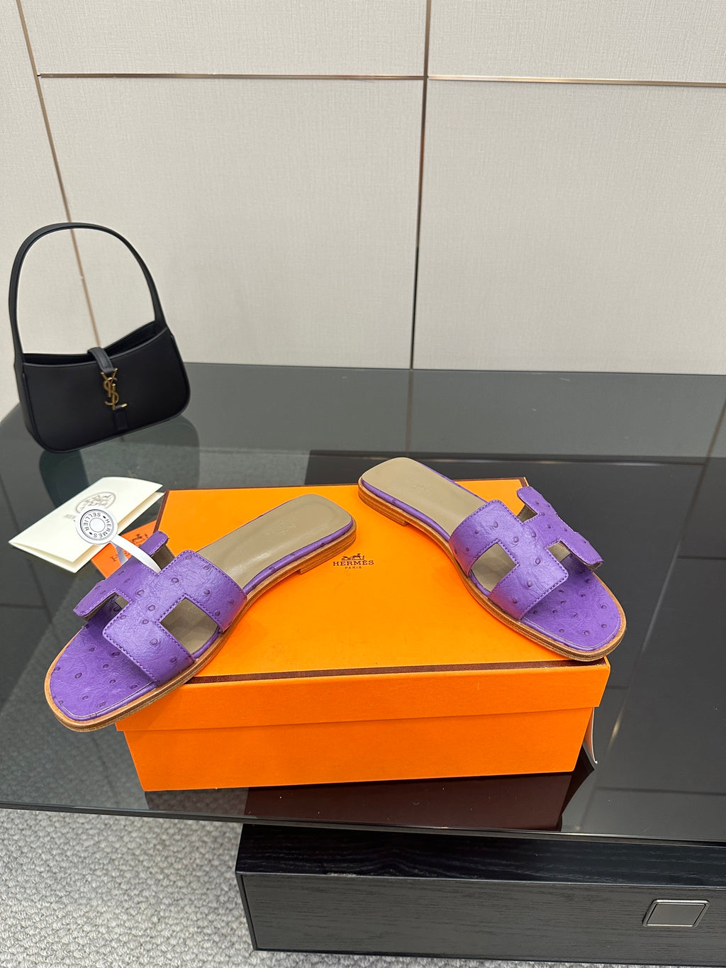 Hermes purple slide sandals with H-style strap, pair shown on orange box with tags