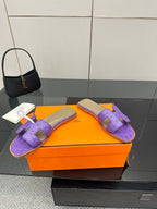 Hermes purple slide sandals with H-style strap, pair shown on orange box with tags