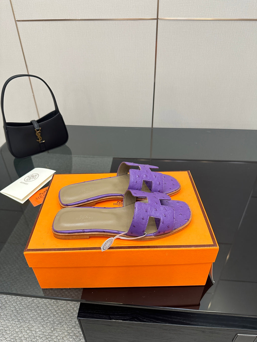Hermes purple slide sandals with H-style cutout strap, one sandal on orange box