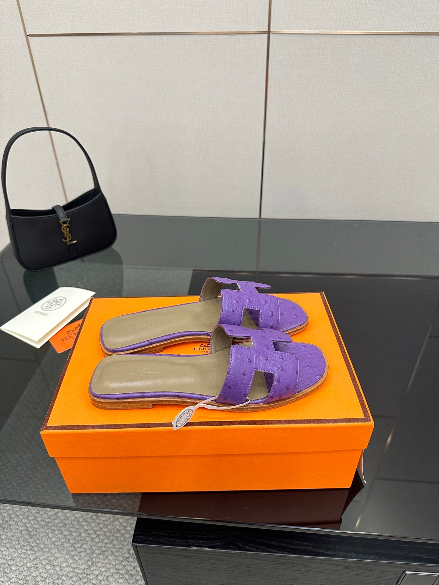 Hermes purple slide sandals with H-style cutout strap, one sandal on orange box