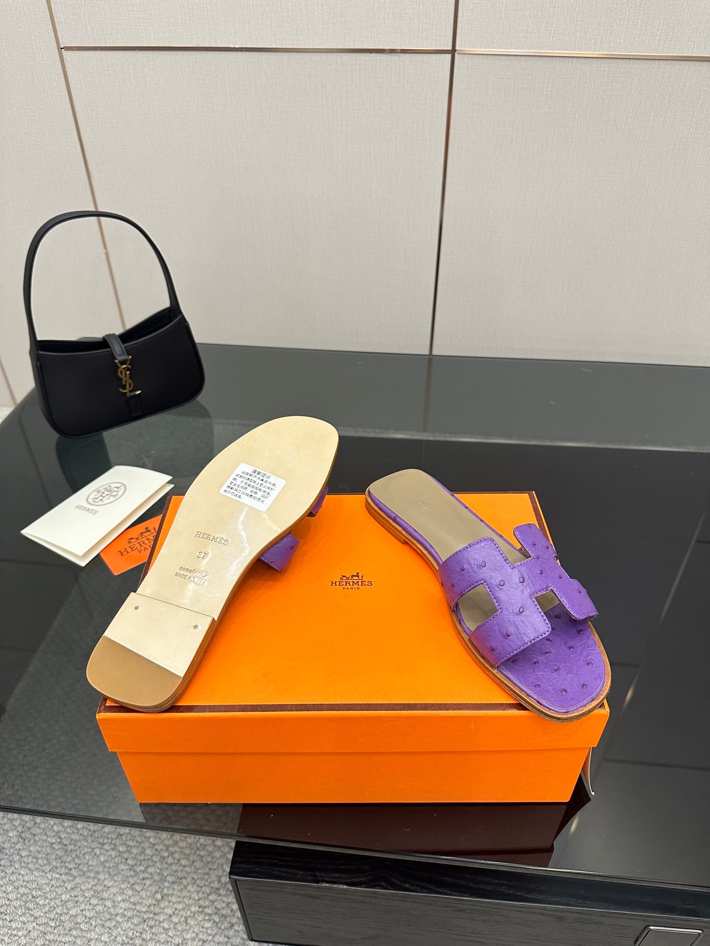 Hermes purple slide sandals, soles view on orange box with one sandal turned over