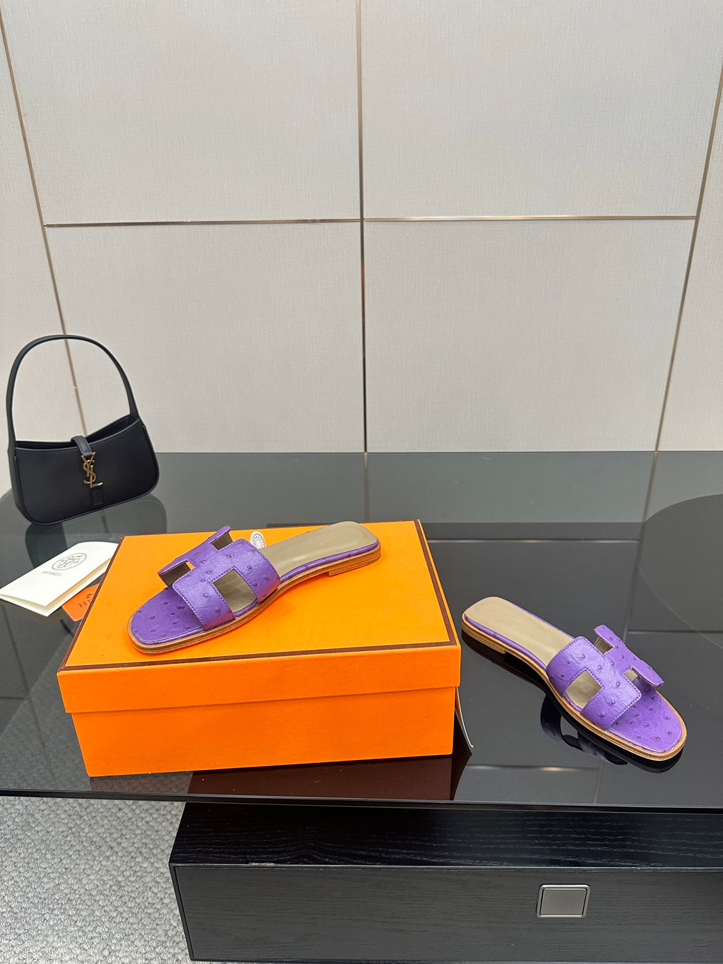 Hermes purple slide sandals with H-style cutout strap, one pair on orange box