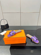 Hermes purple slide sandals with H-style cutout strap, one pair on orange box