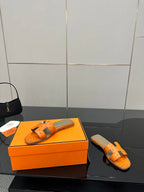 Orange leather slide sandals with openwork strap and square metal buckle detail