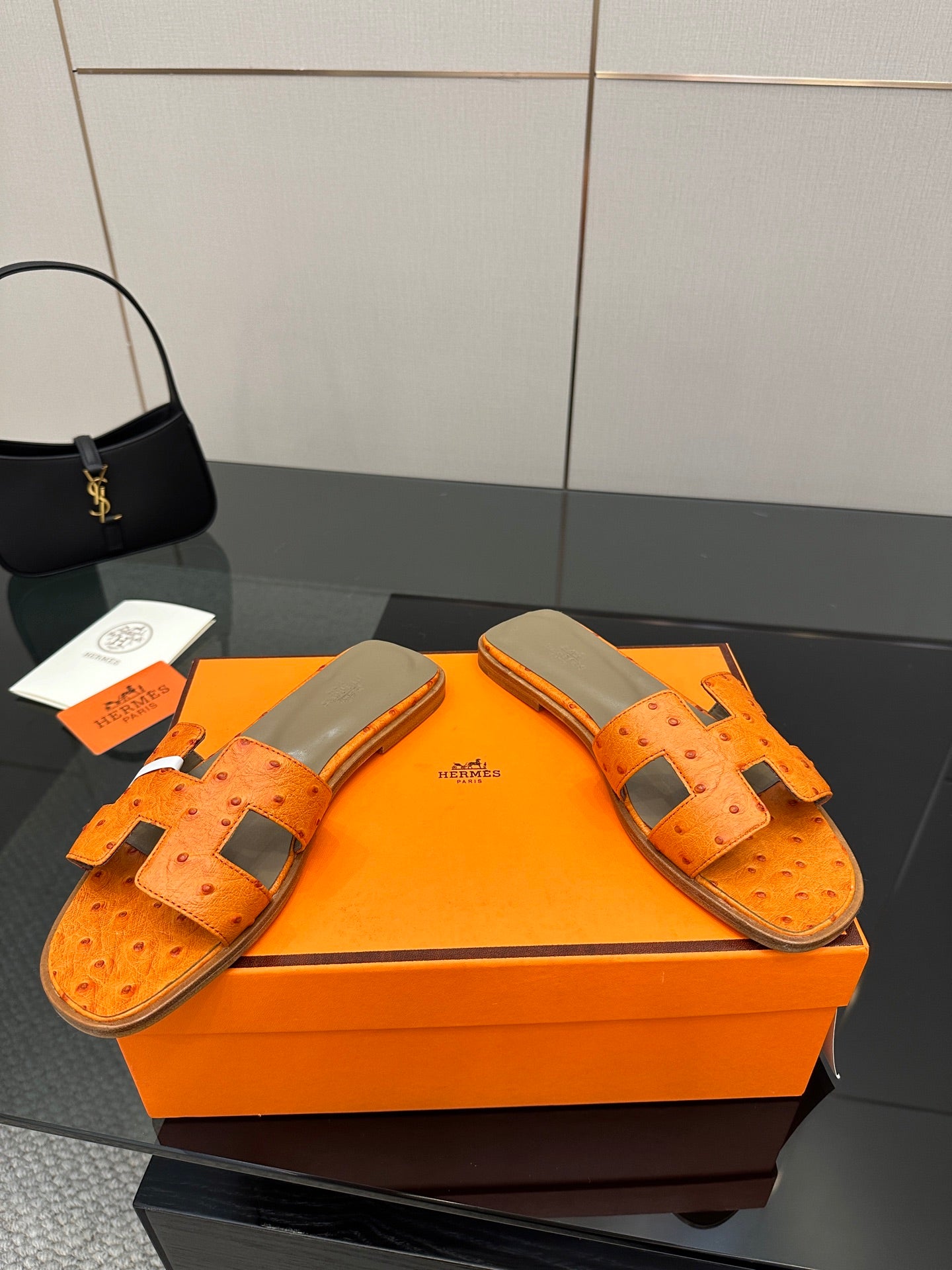 Pair of orange leather slide sandals with square metal buckles and openwork upper
