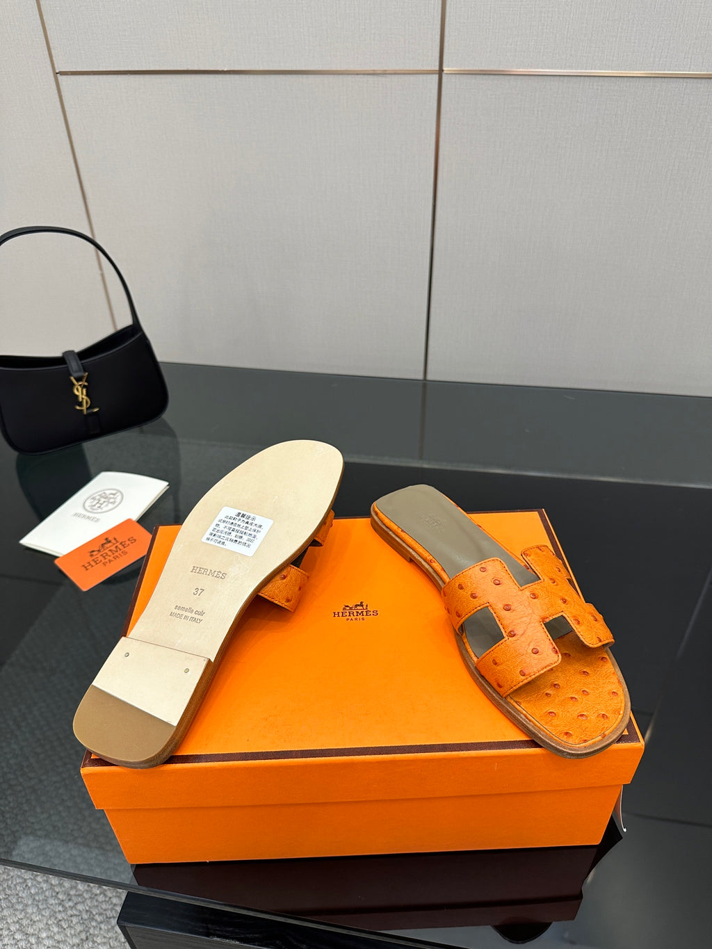 Orange leather slide sandals showing inner sole and square buckle strap detail