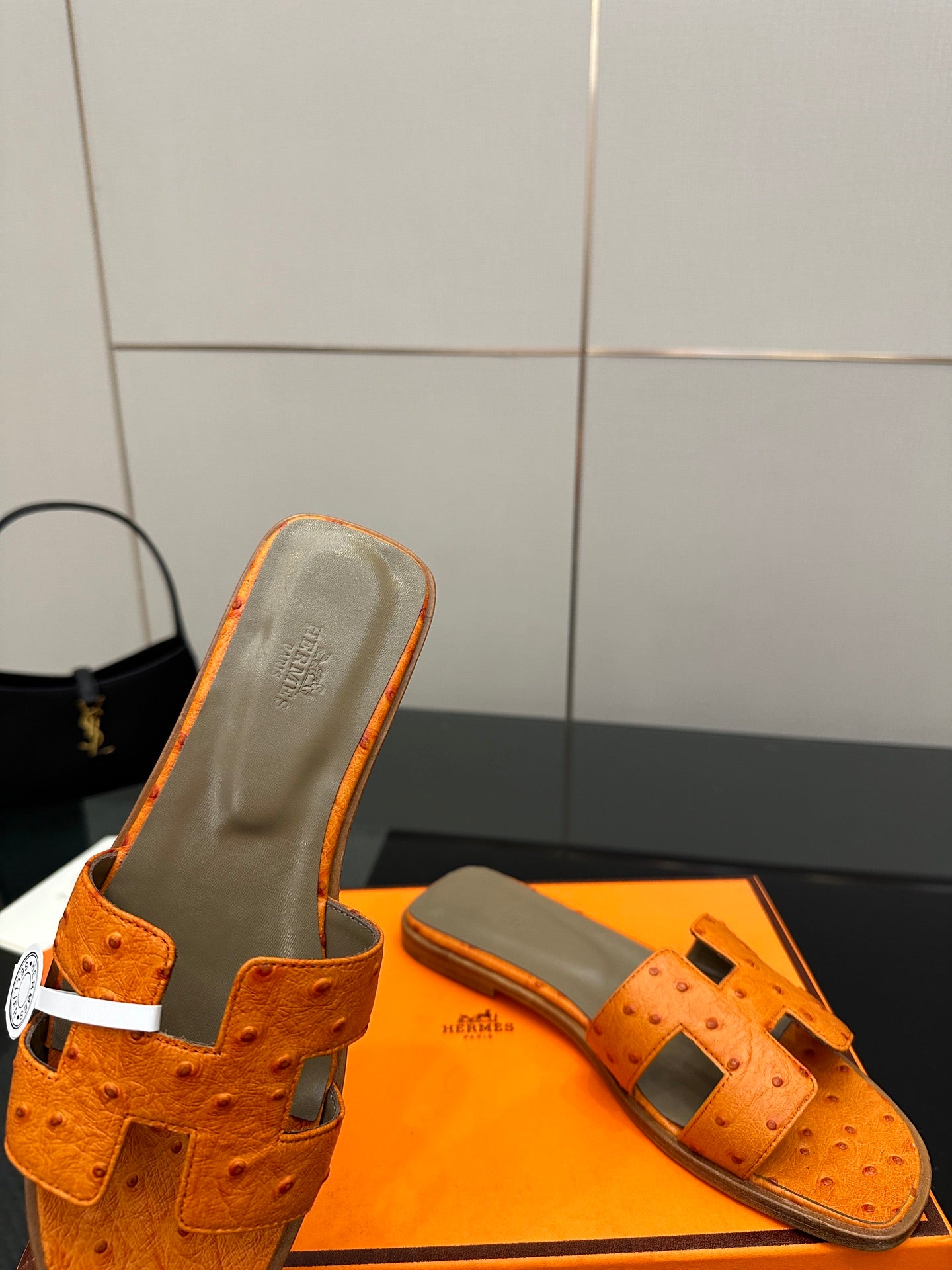 Orange leather slide sandals close-up with perforated texture and metal buckle strap