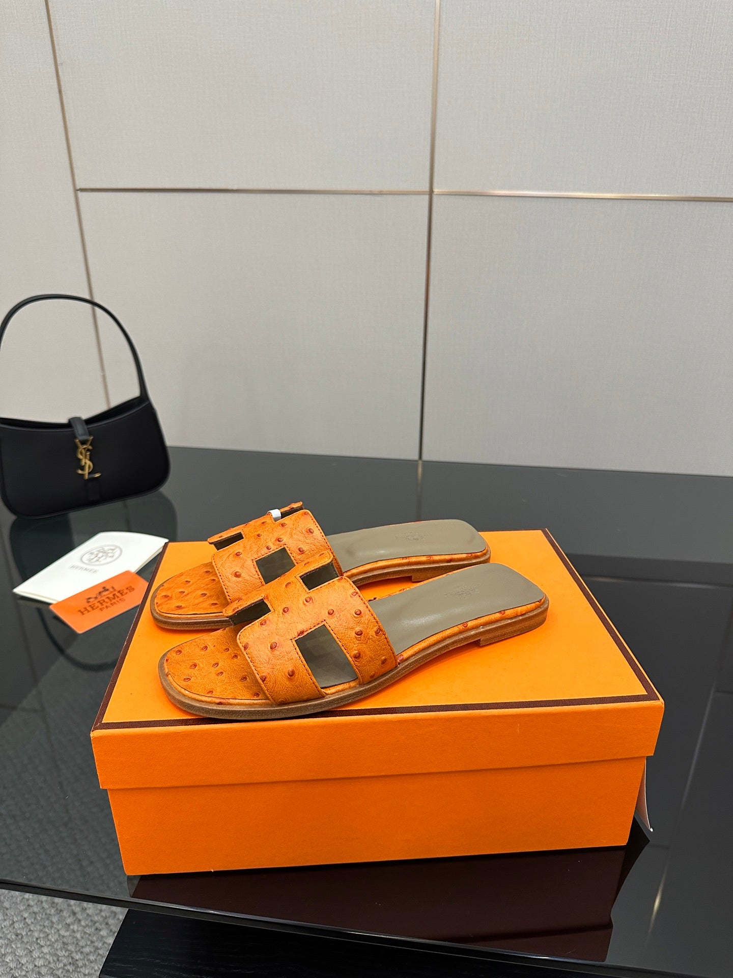 Orange leather slide sandals with wide square strap and metal buckle detail