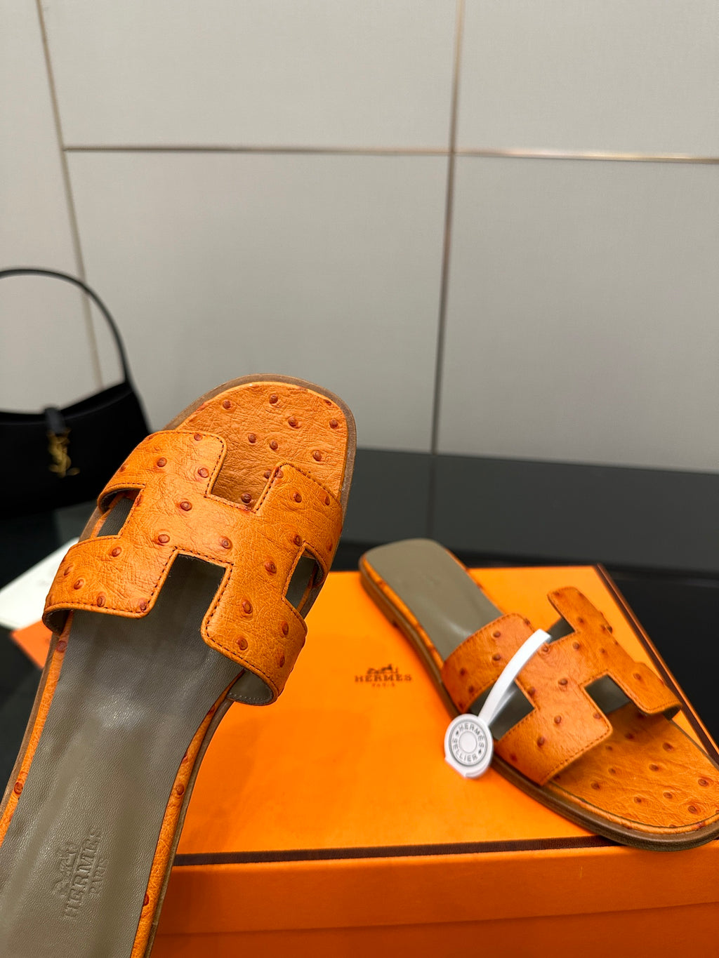 Orange leather slide sandals close-up of toe strap with perforations and metal buckle