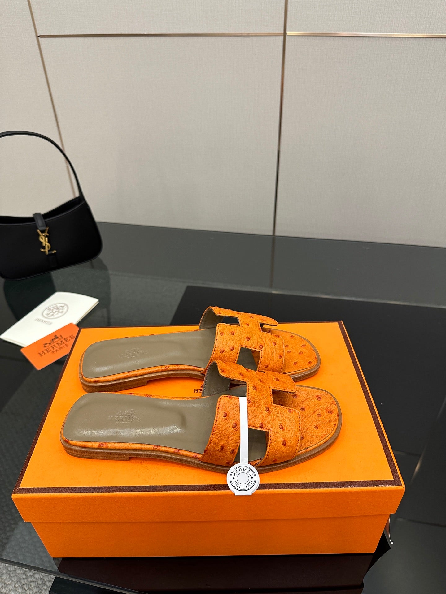 Orange leather slide sandals viewed from above with openwork cross straps and buckles