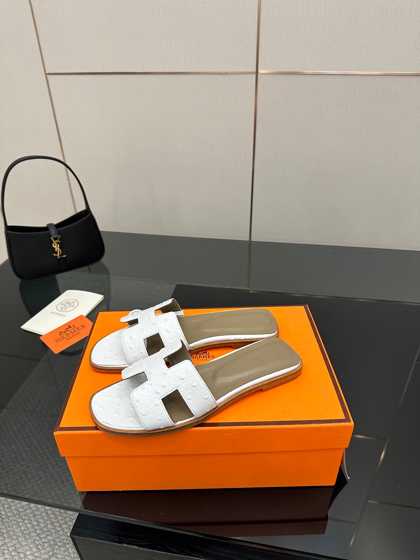 White leather slide sandals, open toe with two straps featuring a metal buckle