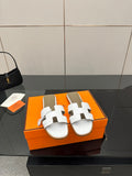 White leather slide sandals with two wide strap cutouts and buckle detail
