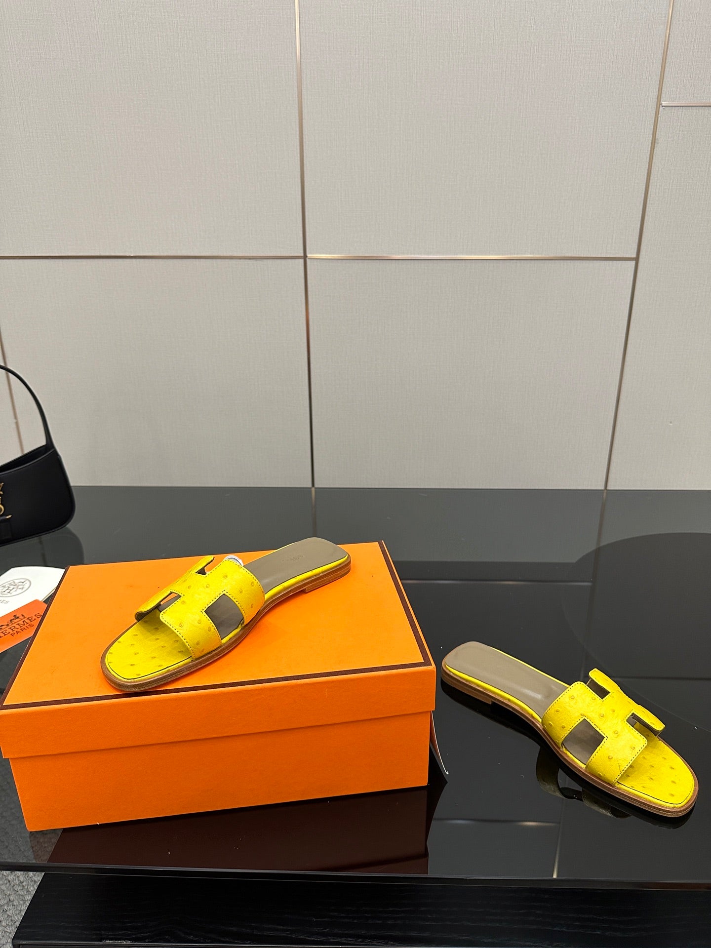 Hermes yellow slide sandals showing side profile, black H straps and gray footbed