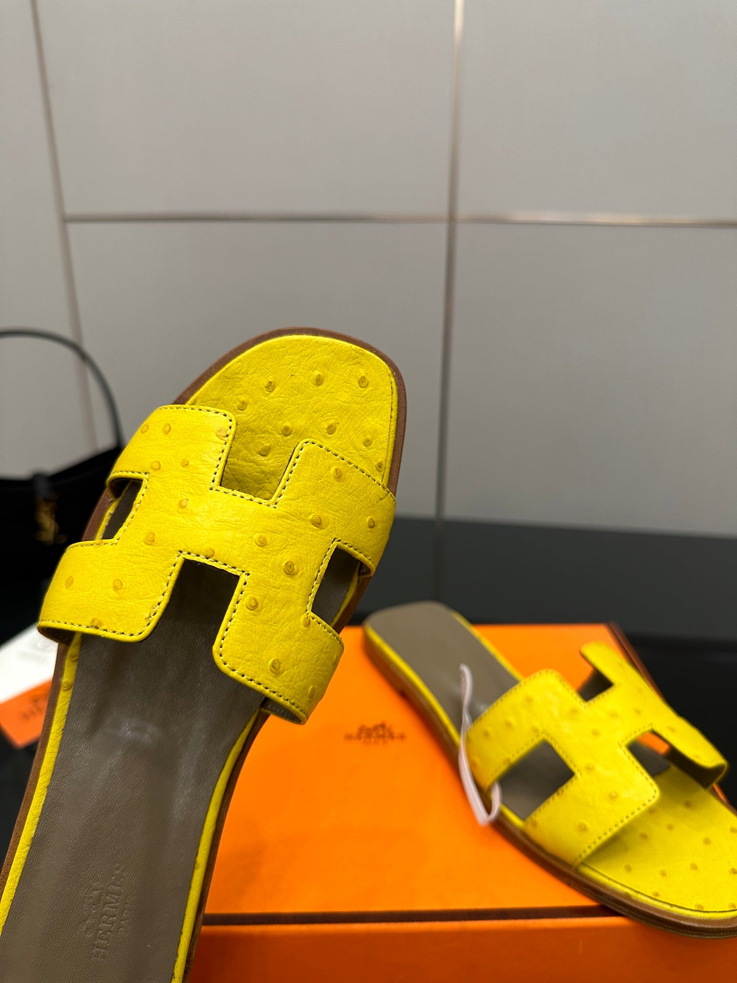 Hermes yellow leather slide sandal close-up with black H strap and gray footbed