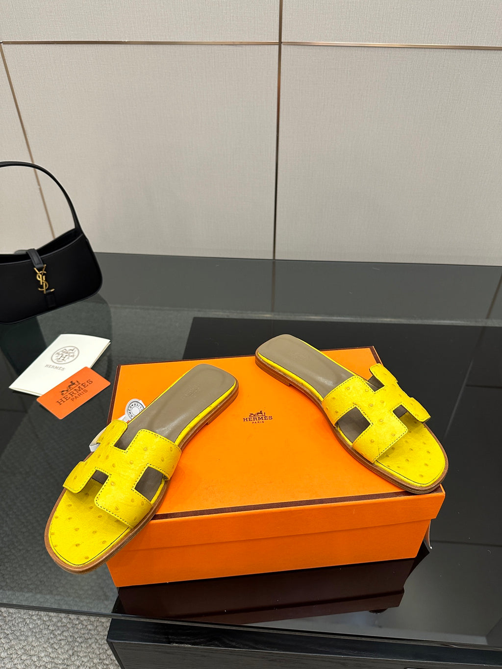 Hermes yellow slide sandals, front view, black H straps and gray footbed