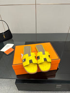 Hermes yellow leather slide sandals with black H-strap buckles and gray footbed
