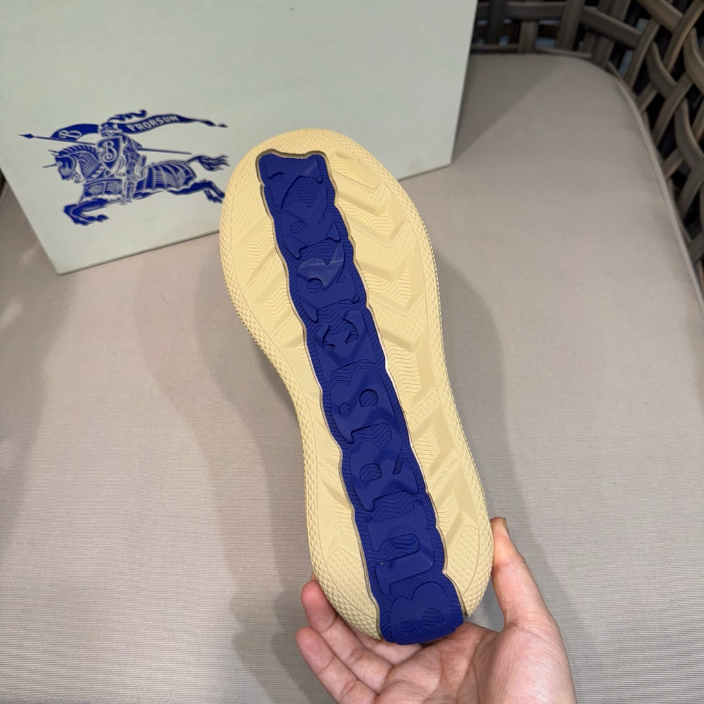 Sneaker outsole tread with blue Burberry-style emblem on light beige base