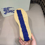 Sneaker outsole tread with blue Burberry-style emblem on light beige base